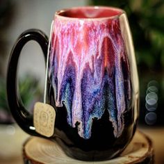 a colorful coffee mug sitting on top of a wooden stump