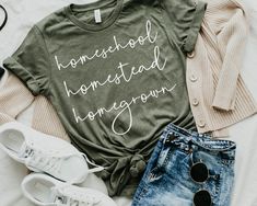 "Embrace the essence of self-sufficiency and learning with our 'Homeschool, Homestead, Homegrown' t-shirt, celebrating the spirit of home-based education and sustainable living for all the hardworking homeschool moms! HOW TO ORDER - Visit photos for sizing and measurements - Select size and color from dropdown menu - Add customization to box if required - Add to cart & proceed to checkout * If you are ordering multiple, then go back to listing and perform steps again for all further products nee Spring Slogan T-shirt For School, Spring School T-shirt With Slogan, Slogan T-shirt For School In Spring, Relaxed Fit T-shirt For End Of School Year, Casual T-shirt With Name Print For School Events, Relaxed Fit T-shirt For School, Spring School Spirit T-shirt For School Events, Educational College T-shirt With Letter Print, Green Text Print T-shirt For School