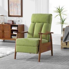 a green recliner chair sitting in a living room next to a wooden cabinet and potted plant