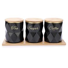 three black canisters sitting on top of a wooden tray