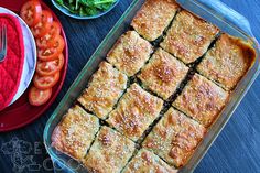 a casserole dish with sliced tomatoes and salad on the side next to it