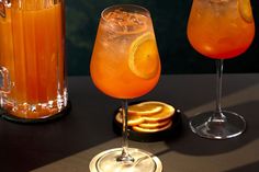 two glasses filled with orange juice sitting next to each other on top of a table