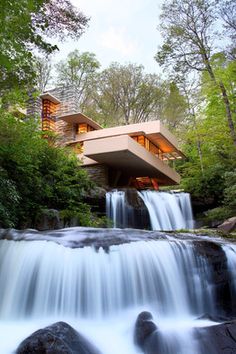 a waterfall in front of a house surrounded by trees