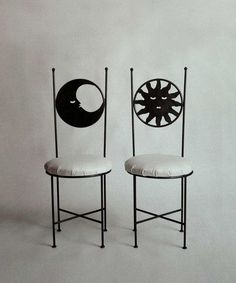 two chairs sitting next to each other in front of a white wall with black circles on it