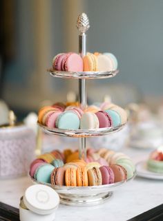 three tiered trays filled with colorful macaroons on top of a table