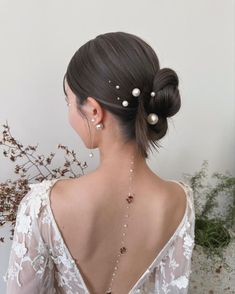 the back of a woman's head with pearls in her hair, wearing a white dress