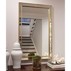 a mirror sitting on top of a wooden table next to a vase and white vase