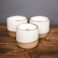 three white candles sitting on top of a wooden table