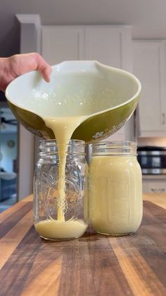 a person pours dressing into jars on a kitchen counter