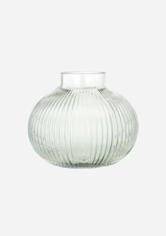 a clear glass vase sitting on top of a white table next to a gray wall