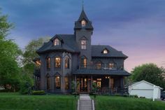 a large gray house sitting on top of a lush green field