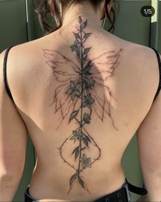 the back of a woman's body with tattoos on it and flowers growing out of it