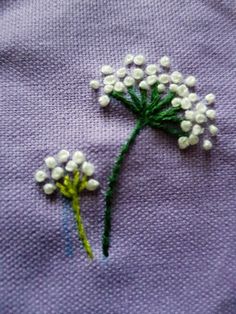 a close up of a piece of cloth with white flowers on it and green stems