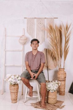 a man sitting on a stool next to some plants