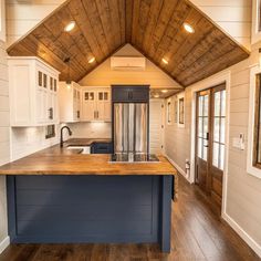 a kitchen with an island in the middle and wood flooring on the walls, along with white cabinets