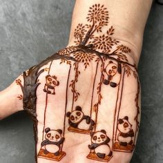 a person's hand painted with brown and white designs on it, depicting pandas in cages