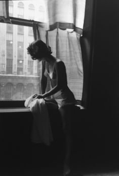 a woman sitting on a window sill looking out the window