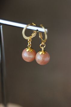 Simple and delicate dangle earrings with natural round rosa-beige moonstone/sunstone 10-11 mm beads, small gold tone bead caps and round gold tone stainless steel lever back earring hooks. Perfect for everyday wear or a great gift for someone special! *The total lenght of earrings is about 32 mm including earring hooks. Other earrings of my shop you can see here: https://www.etsy.com/shop/NaTavelli?section_id=13757927  Thanks for visit. Elegant Sunstone Jewelry, Round Shape, Elegant Round Sunstone Jewelry, Elegant Apricot Dangle Earrings, Elegant Apricot Dangle Jewelry, Sunstone Crystal, Beige Earrings, Small Dangle Earrings, Earrings Elegant, Moonstone Earrings