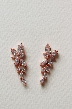 two pairs of diamond earrings sitting on top of a white surface