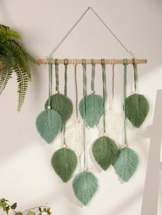 a green and white dream catcher hanging on a wall next to a potted plant