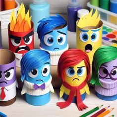 some very cute looking toy figures on a table with colored markers and crayons