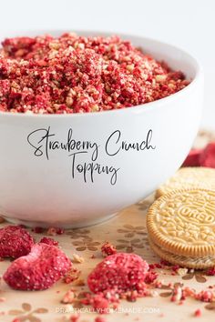 a white bowl filled with raspberry crunch topping next to a cookie