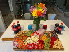 a wooden tray topped with lots of food and drinks next to a vase filled with flowers