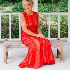 a woman in a red dress sitting on a bench