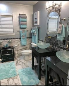 a bathroom with two sinks, mirrors and blue towels on the rack in front of it