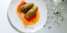 two pickles on a white plate with sauce