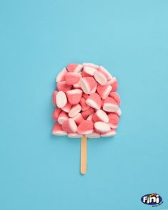 pink and white marshmallows on a stick against a blue background