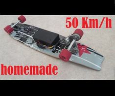 a skateboard with red wheels is laying on the ground and has an electronic device attached to it