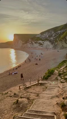 stairs lead down to the beach as people walk on the sand and in the water