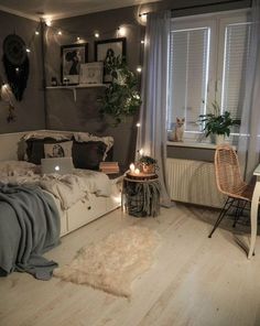 a bedroom with a bed, desk and chair in it's center area is lit up by string lights