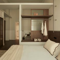 there is a bed with white sheets and pillows in the room that has wooden shelves above it