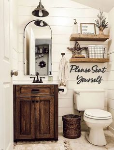 a white toilet sitting next to a wooden cabinet in a bathroom under a large mirror