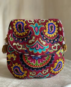 an embroidered purse with tassels and beads on the handle is sitting on a white surface