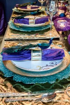 the table is set with purple and blue plates, silverware, and napkins