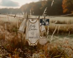 a baby's bodysuit hanging on a barbed wire fence in the middle of a field