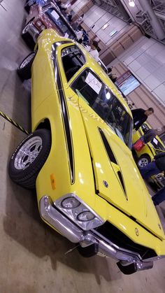 an old yellow car is parked in a garage