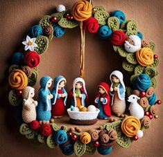 a crocheted nativity scene hanging on a wall in front of a brown background