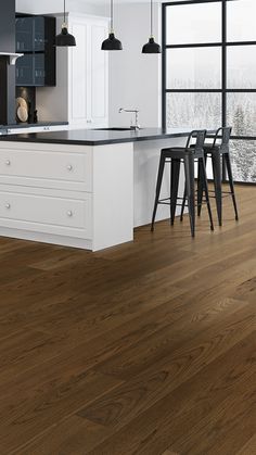 a large kitchen with white cabinets and wood flooring on the walls, along with bar stools