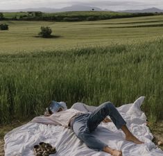 a man laying on top of a blanket in a field