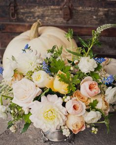 a vase filled with lots of flowers on top of a table next to a pumpkin