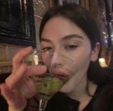 a woman holding a wine glass filled with green liquid