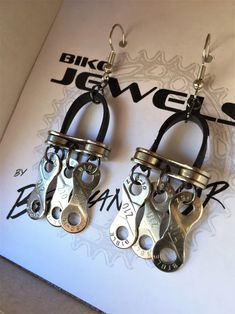 pair of silver and black metal earrings on top of a white piece of paper with the words bike lover written below it