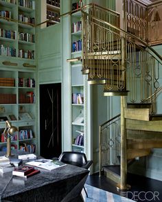 a living room filled with furniture and bookshelves next to a spiral stair case