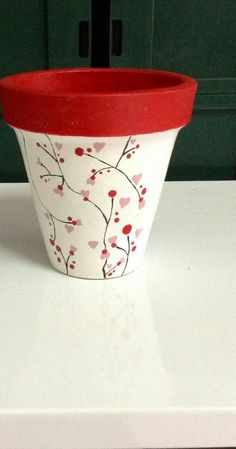 a red and white flower pot sitting on top of a counter