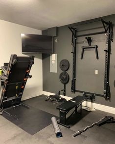 a home gym is shown with equipment in the corner and on the wall, as well as an overhead television