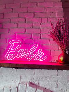 a pink neon sign that says razzle on top of a shelf next to a vase with flowers